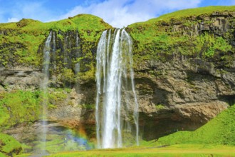 The famous Seljalandsfoss waterfall. Travel to exotic Iceland. Magnificent rainbow appears in the