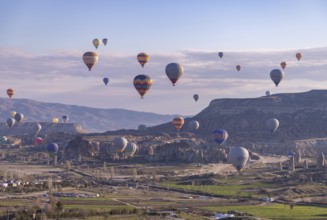 A picture of colorful hot air balloons flying over the landscape of Goreme Historical National Park