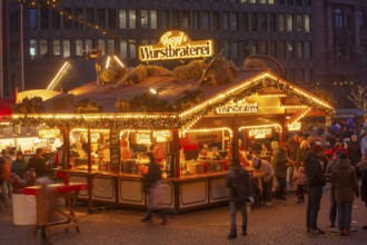 Sausage roasting stand with many people at the Bremen Christmas market at dusk, Bremen, Germany
