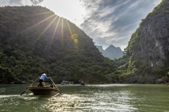 Boats in the river under bright sunlight and green mountains, rowing boats for tourists in Halong