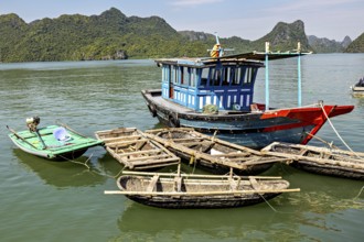 Fishing boats float peacefully on green waters surrounded by steep, forested hills, fishermen and