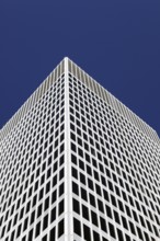 White tower block rises into the blue sky