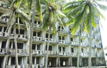 Abandoned hotel in coastal recreation area in Southeast Asia. Palm trees and failed otel business