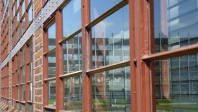 Red window frames reflecting a modern building on a bright sunny day