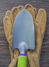Hand spade leather safety gloves on wooden board agriculture concept