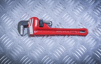 Pipe wrench on fluted metal plate construction concept