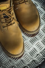 Pair of leather protective boots on fluted metal sheet