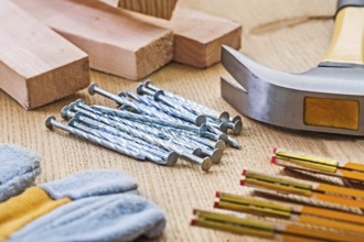 Close up view on set of carpentry tools hammer nails glove meter planks on wooden board