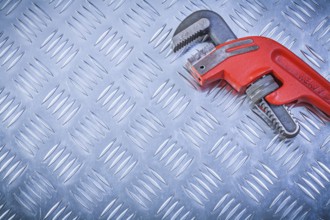 Metal pipe wrench on channeled metallic sheet maintenance concept
