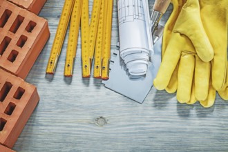 Red bricks leather protective gloves wooden meter construction drawings bricklaying trowel building
