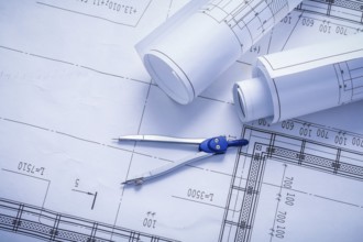 Vertical version compass and rolled blueprints close up