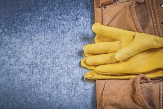 Pair of protective gloves toolbelt on metallic background construction concept