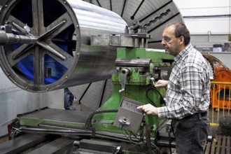An older employee in the metal industry works on a CNC milling machine, Senior, 65, years,
