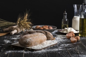 Beautiful still life with different kinds of bread, grain, flour on weight, ears of wheat, pitcher