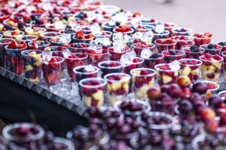 Rows of colorful fruit cups filled with fresh berries displayed on a market stall in the seaside