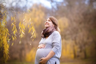 Happy young smiling pregnant woman in autumn park