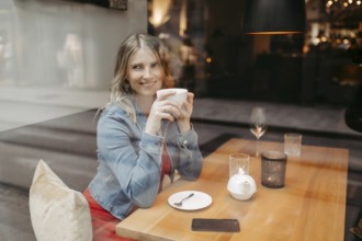 Blonde, attractive woman, 40+, sitting in a coffee house by the window