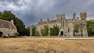 Expansive view of a castle with ivy and a cloudy sky, Pirou Castle in Normandy, France