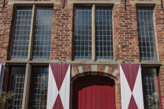 Red brick building with large mullioned windows and red and white shutters, Xanten, Lower Rhine,