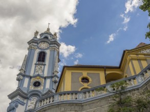An impressive baroque church tower and a building that both break through the blue sky, Dürnstein,