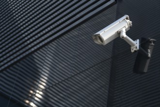 Photo of Modern CCTV camera on a wall. A blurred night cityscape background. Concept of
