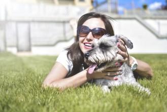 Pretty adult caucasian happy woman resting in the park on a sunny day with her beloved dog. Female