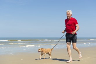 Senior runner with dog at the beach