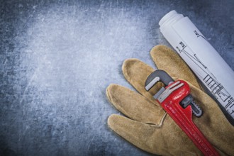Monkey wrench protective gloves blueprints on scratched metallic background plumbing concept
