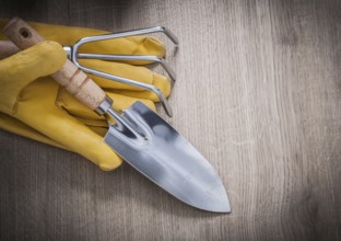 Stainless hand trowel rake yellow leather working gloves on wood board agriculture concept
