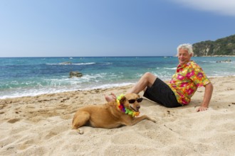 Relaxing elderly man with dog laying at the beach