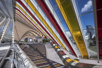 Colourful glass roof adorns the sides of a modern railway station with a view of the city, Liège,