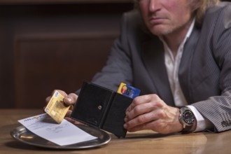 Man in suit pays the bill with credit card, Mindelheim, Bavaria, Germany