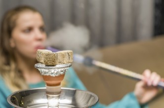 Woman in background blurred, smoking traditional Hookah (Narguile, Shisha, Chicha, Arguile),