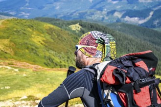 Man hiker on the trail hiking the mountain. A man sitting on a trail and looks at the beautiful