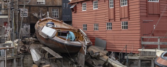 Spakenburg, The Netherlands - Fedbruary 19, 2021: Man inspecting historic ship at wooden ship wharf