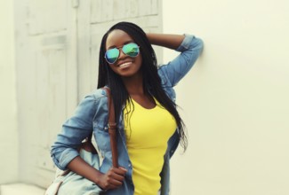Portrait of happy stylish young african woman in casual clothing, glasses with dreadlocks, backpack