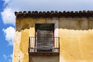 Old Iron Balcony in Aged Yellow Plaster Facade. Old abandoned house