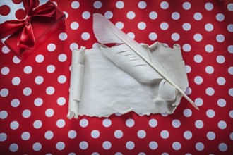 Present box vintage paper roll feather on polka-dot red tablecloth celebrations concept
