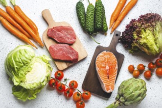 Assorted food raw products: vegetables, beef meat steak, fish salmon fillet on wooden cutting
