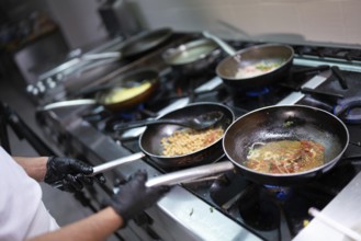 Chef cooking with various ingredients in pans on a stove