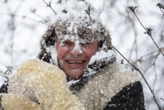 A frozen man covered in winter snow smiles and looks at the camera. The first snow has fallen. A