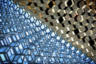 Compact geometric patterns in a glass architecture reflecting blue and gold tones, Harpa Concert