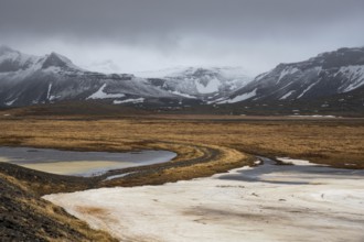 Icelandic dramatic landscape with frozen lake and mountains covered in snow in winter Iceland