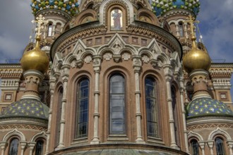 Close-up of a church with beautiful windows, golden domes and colourful mosaics under a cloudy sky,