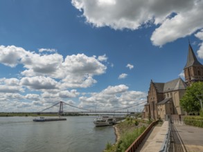 Historic church with a bridge and a ship on the river under a cloudy sky, emmerich, lower rhine,