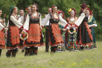 People in traditional costumes dance bulgarian horo a meadow near the village of Varvara