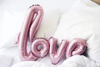 Large pink inflated letters LOVE on linens on the bed. The trend for Valentine's Day