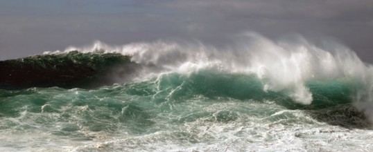 High wave piles up metres high in front of rolling over. Landscape format. High wave towers metres