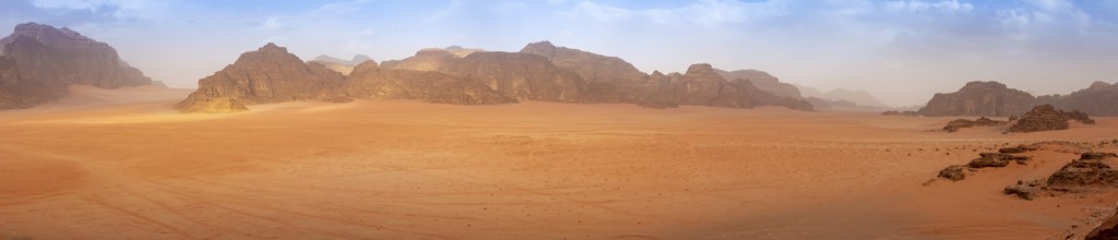 Panorama wide angle of an empty Wadi Rum desert in spring, with some clouds in the air. Travel and