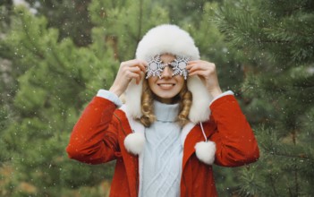 Winter day, happy smiling young woman with snowflakes decoration toys having fun enjoys snow, warm